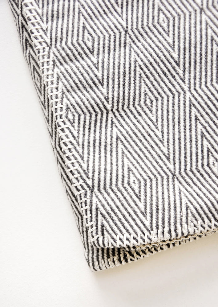 2: Cotton blanket with allover geometric diamond pattern in black and white, with whipstitched trim