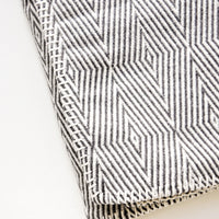 2: Cotton blanket with allover geometric diamond pattern in black and white, with whipstitched trim