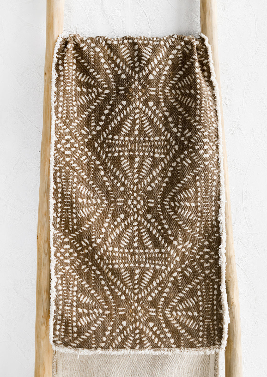 1: A brown canvas table runner with white resist pattern.