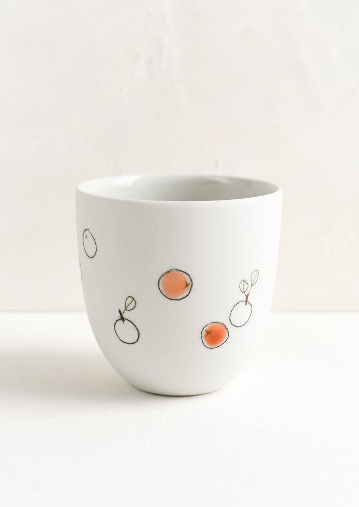 A small porcelain cup with hand drawn grapefruits.