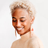 2: Model wears peach and orange fringe beaded earrings and peach colored sweater.