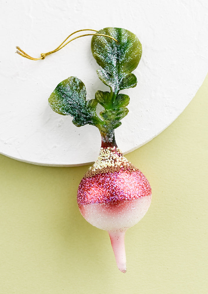 A decorative glass ornament in shape of radish with leaves.