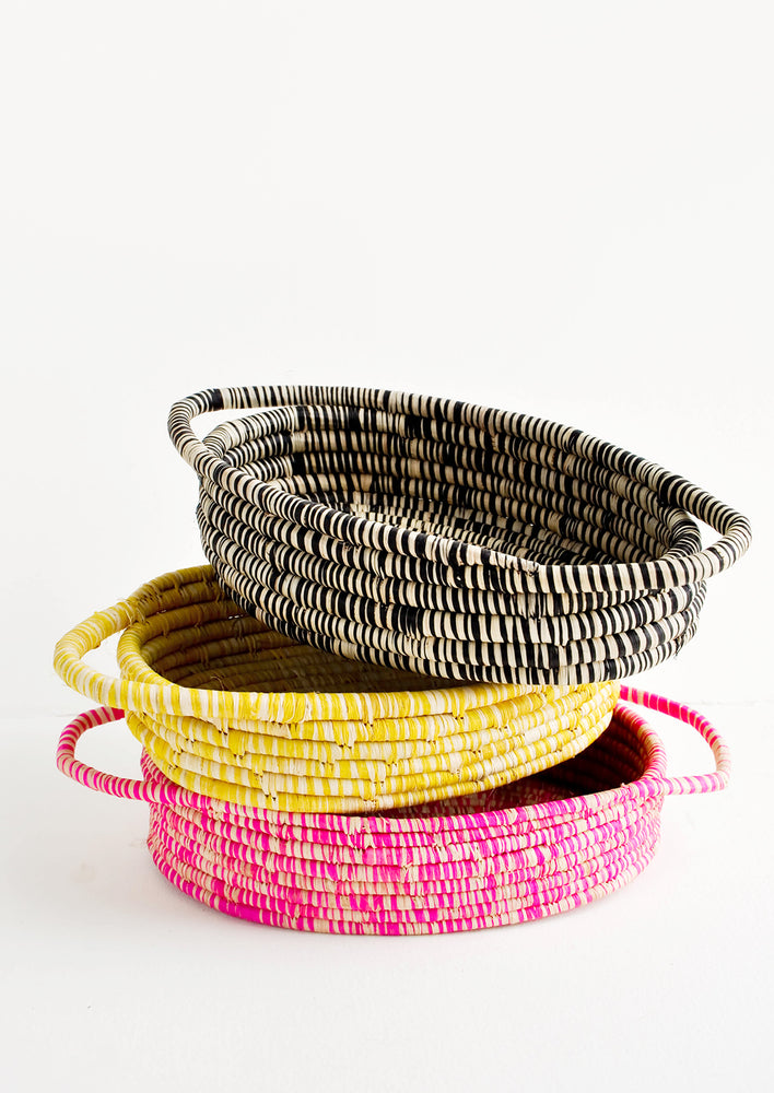 Stack Of Oval Shaped Raffia Baskets in black, yellow, and pink.