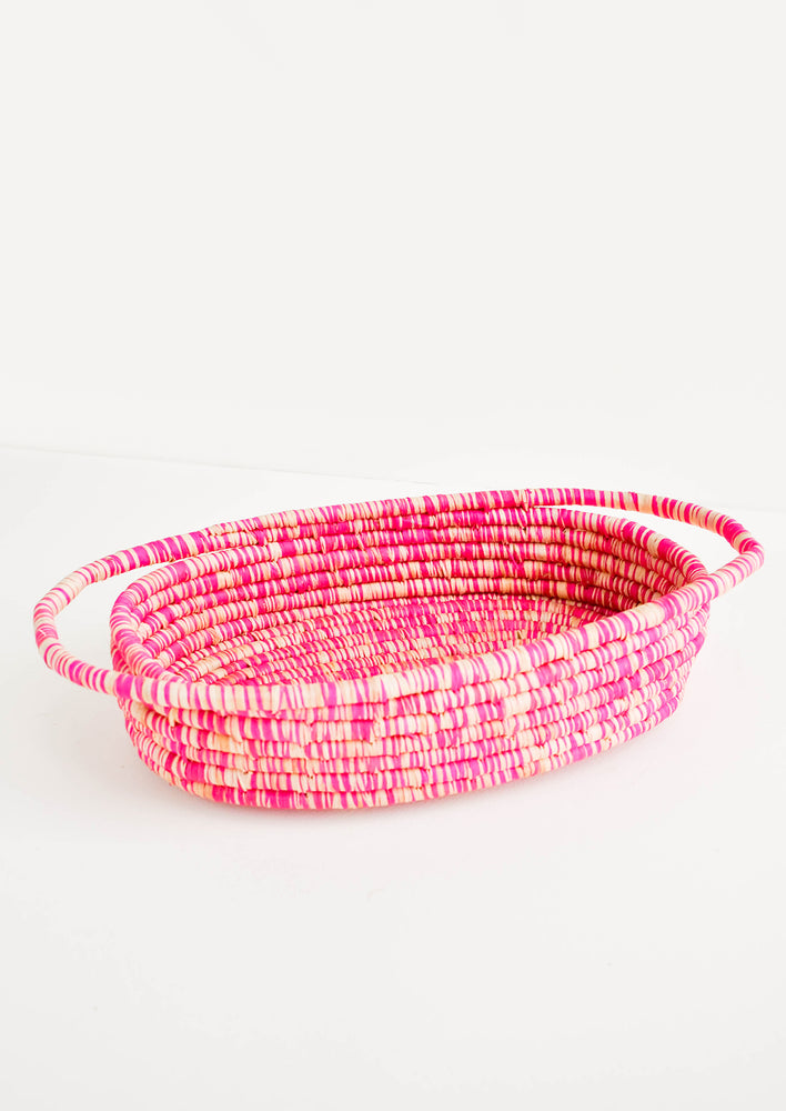 Pink: Oval Shaped, Shallow Raffia Basket with two handles at either end in Pink 