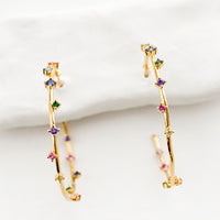 1: A pair of gold hoop earrings with colored crystals wrapping around the hoop sporadically.