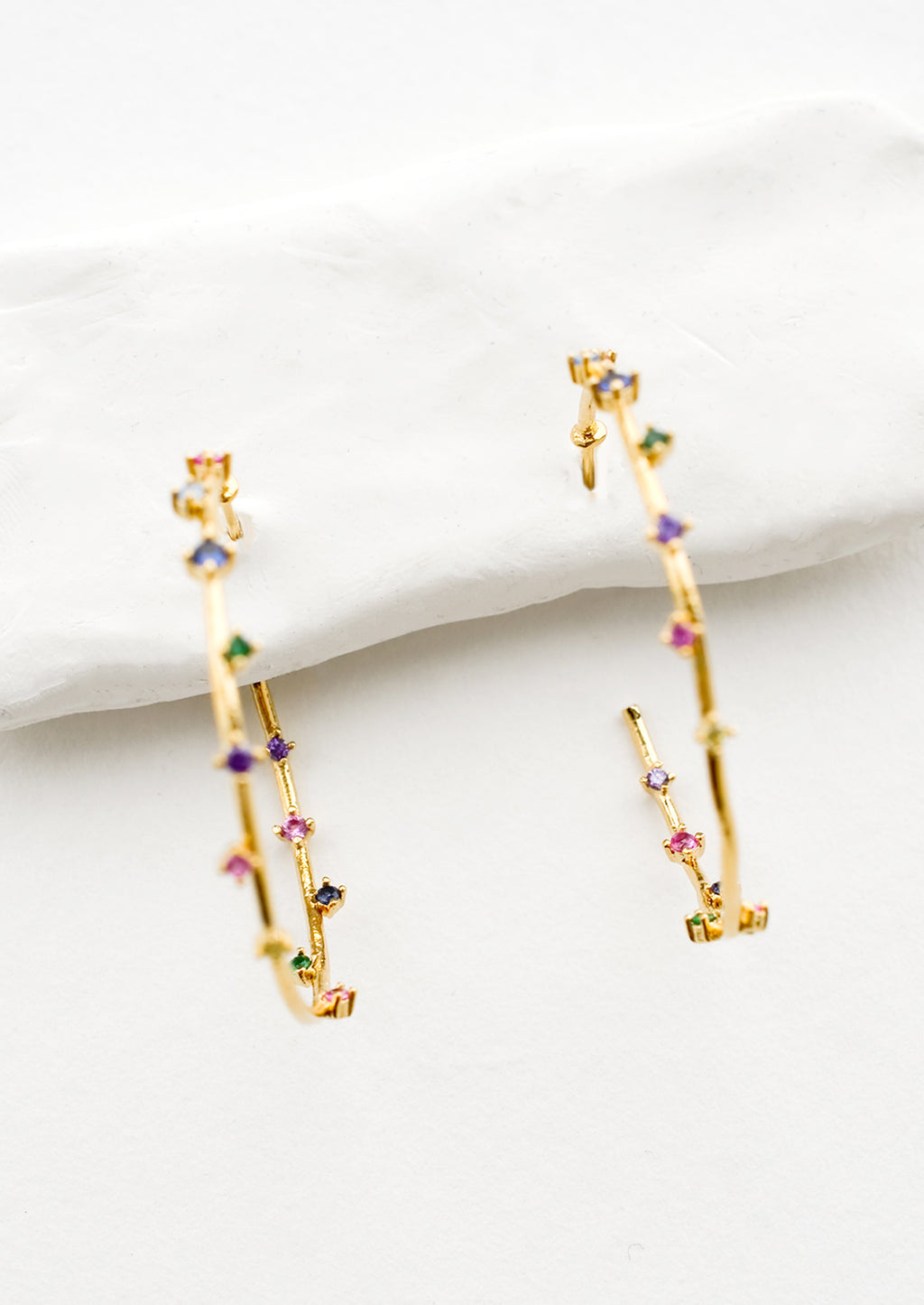 4: A pair of gold hoop earrings with colored crystals wrapping around the hoop sporadically.