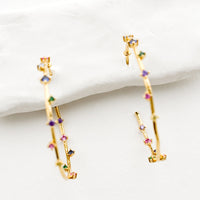 4: A pair of gold hoop earrings with colored crystals wrapping around the hoop sporadically.
