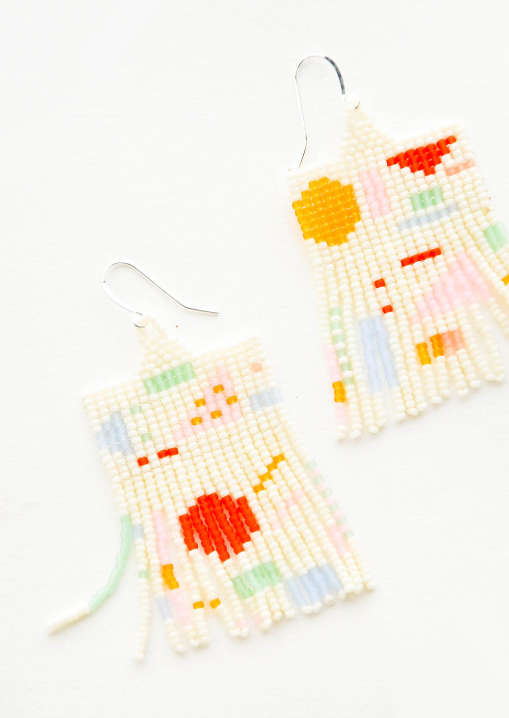 1: Cream colored glass bead fringe earrings with pattern of colorful geometric shapes on silver ear wire.