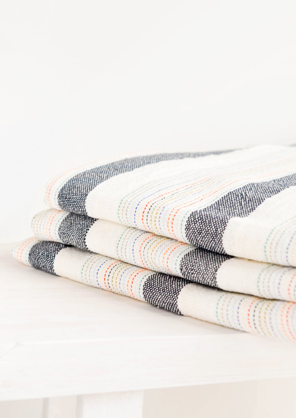 2: Stack of Cotton Turkish Towel in Natural & Charcoal with Rainbow Colored Stitching - LEIF
