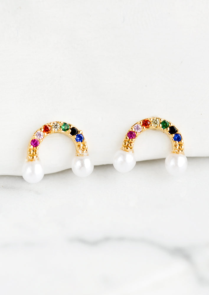 A pair of stud earrings in multicolor rainbow arc with pearl "clouds".