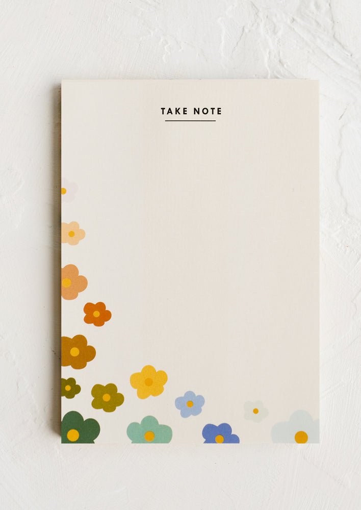 A notepad with rainbow colored flowers, text at top reads "Take Note".