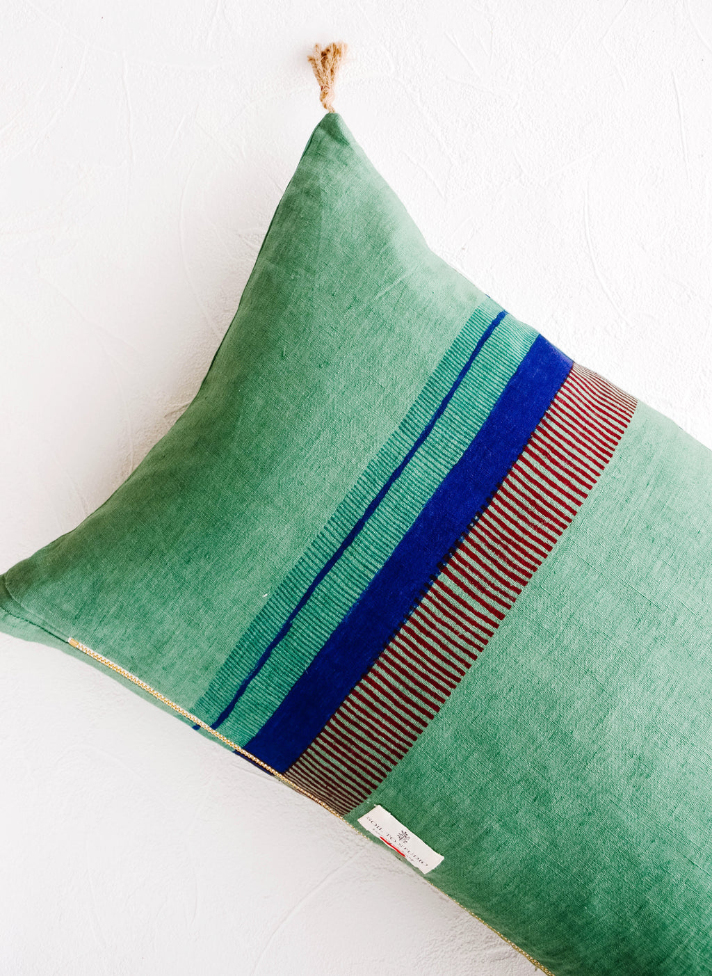 3: Back of linen throw pillow showing a series of block printed stripes and exposed brass zip closure