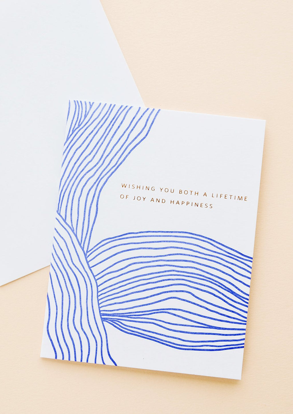 1: White greeting card with wavy cobalt blue line pattern and gold text reading "Wishing you both a lifetime of happiness"