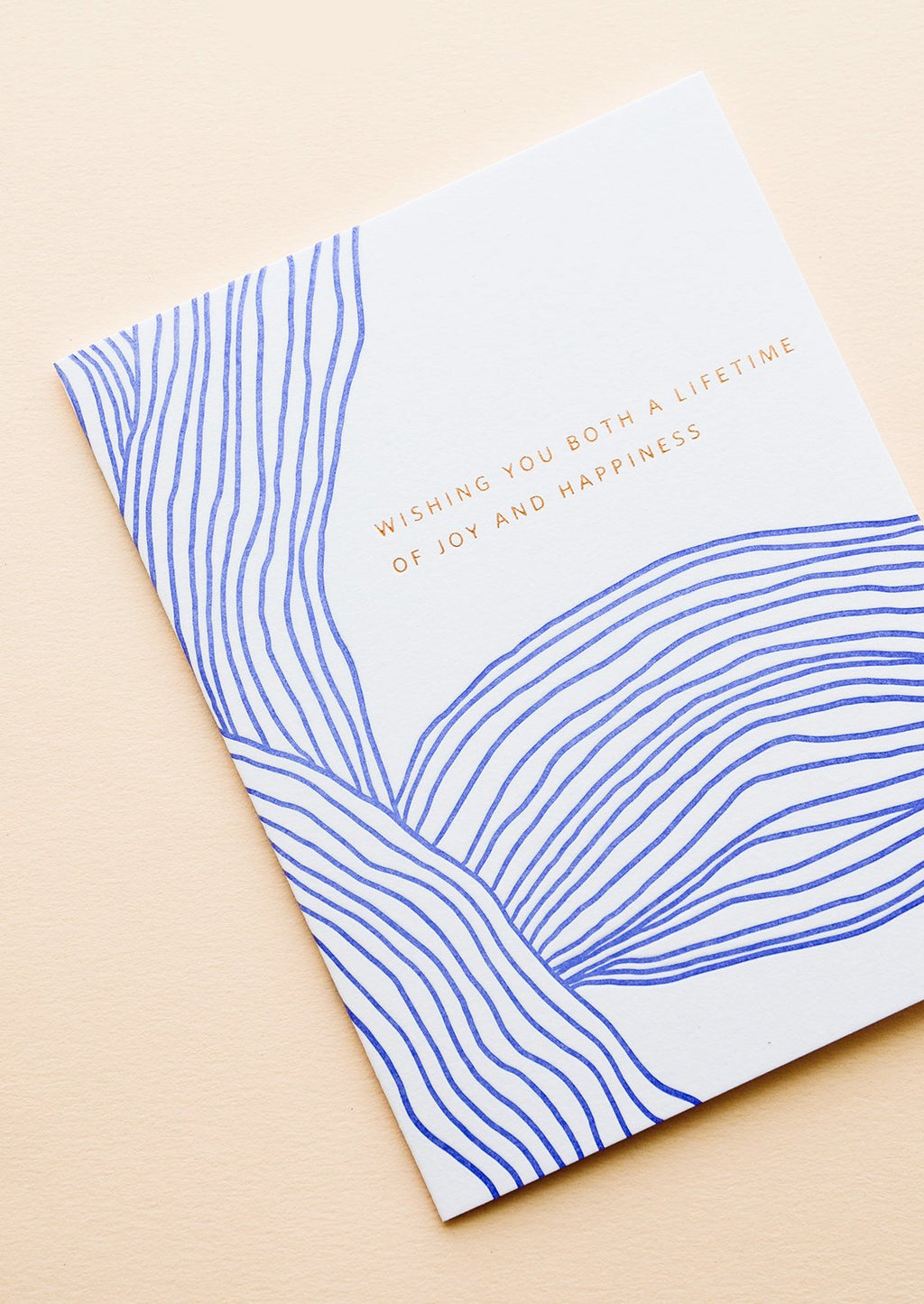 2: Greeting card with wavy cobalt blue line pattern and gold text reading "Wishing you both a lifetime of happiness"