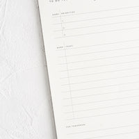 2: A white notepad with guided prompts for listing daily tasks and priorities.