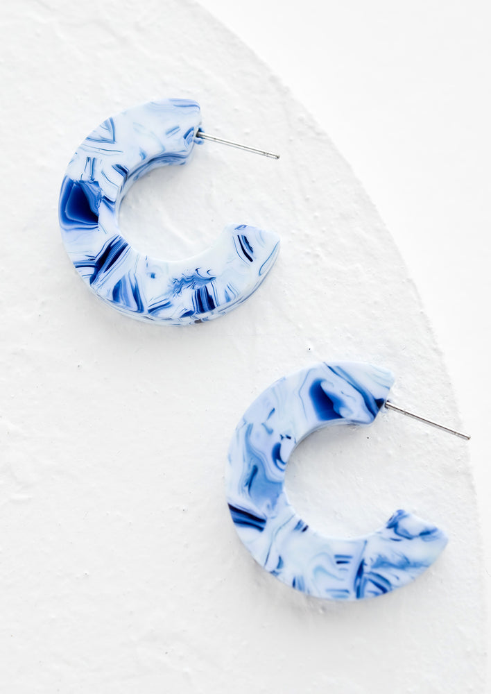 A pair of acetate hoop earrings in blue and white.