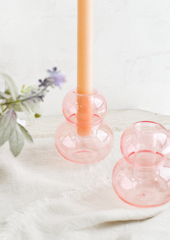 Blush Pink: Bubble shaped glass taper candle holders in pink, on a table.