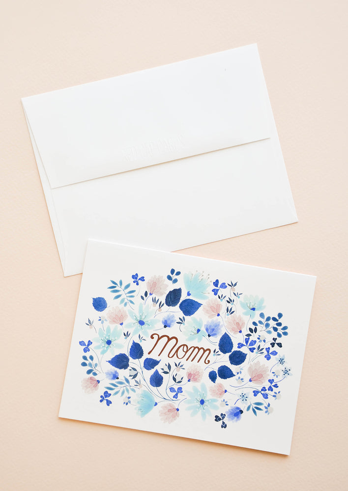 Greeting card with blue floral print frame around "Mom" printed in copper text