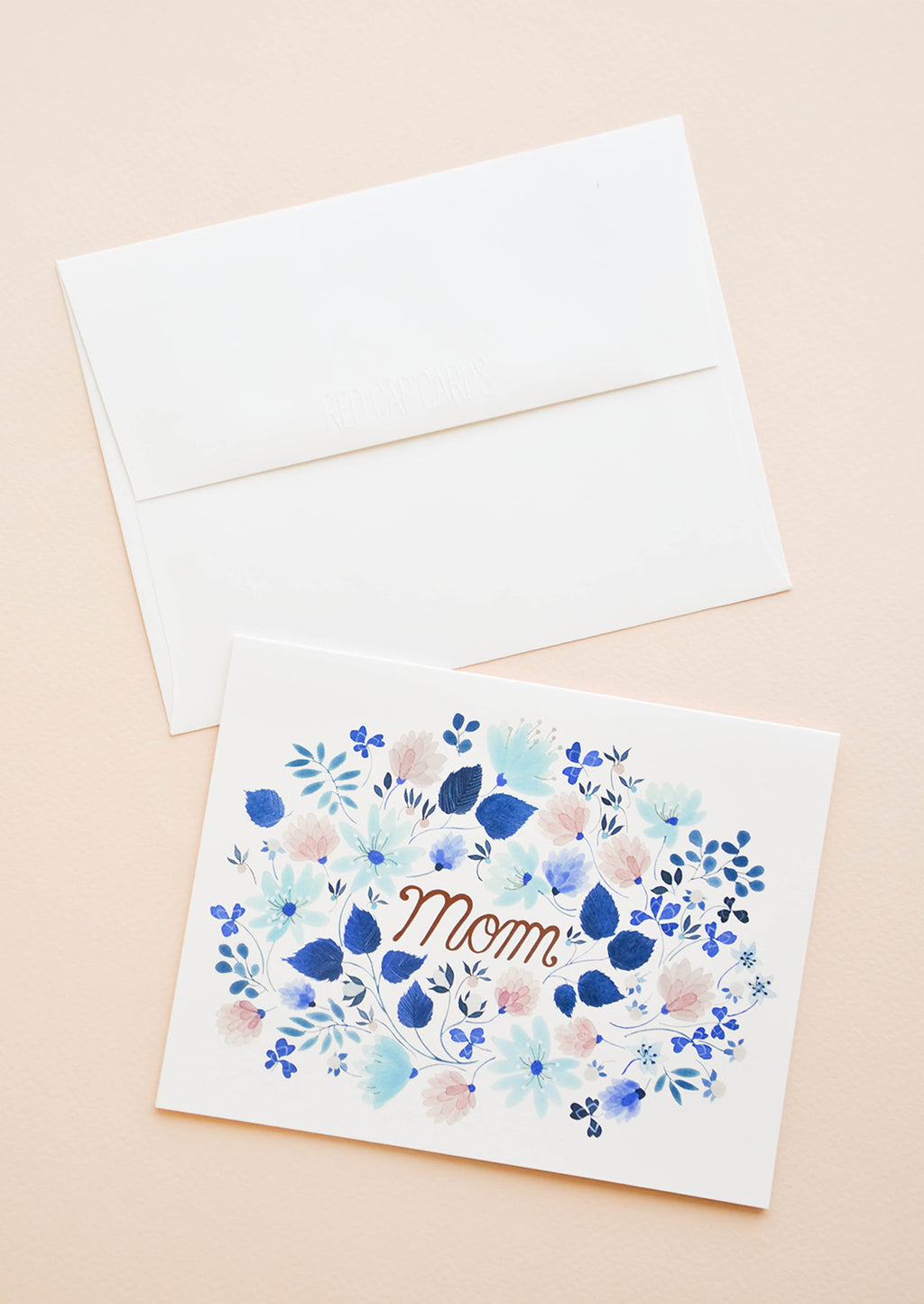 1: Greeting card with blue floral print frame around "Mom" printed in copper text