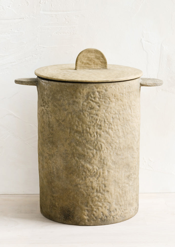 1: A texture brown clay storage jar with tab-like side handles and detail on lid.