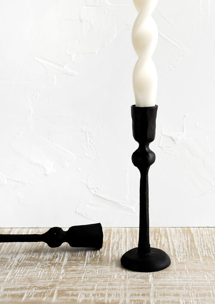 Black cast iron candle holders in spindly, carved silhouette.