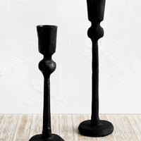 2: Black cast iron candle holders in spindly, carved silhouette.