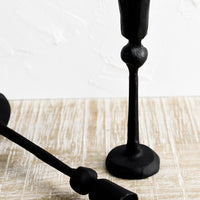 3: Black cast iron candle holders in spindly, carved silhouette.