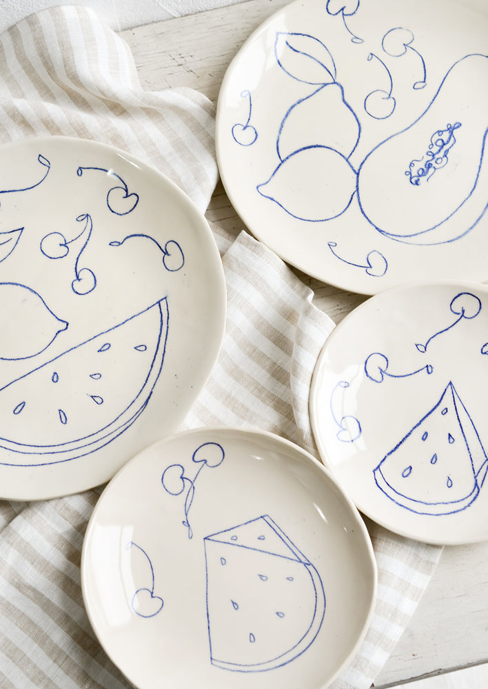 2: Ceramic side & dinner plates with still life fruit drawings in blue.