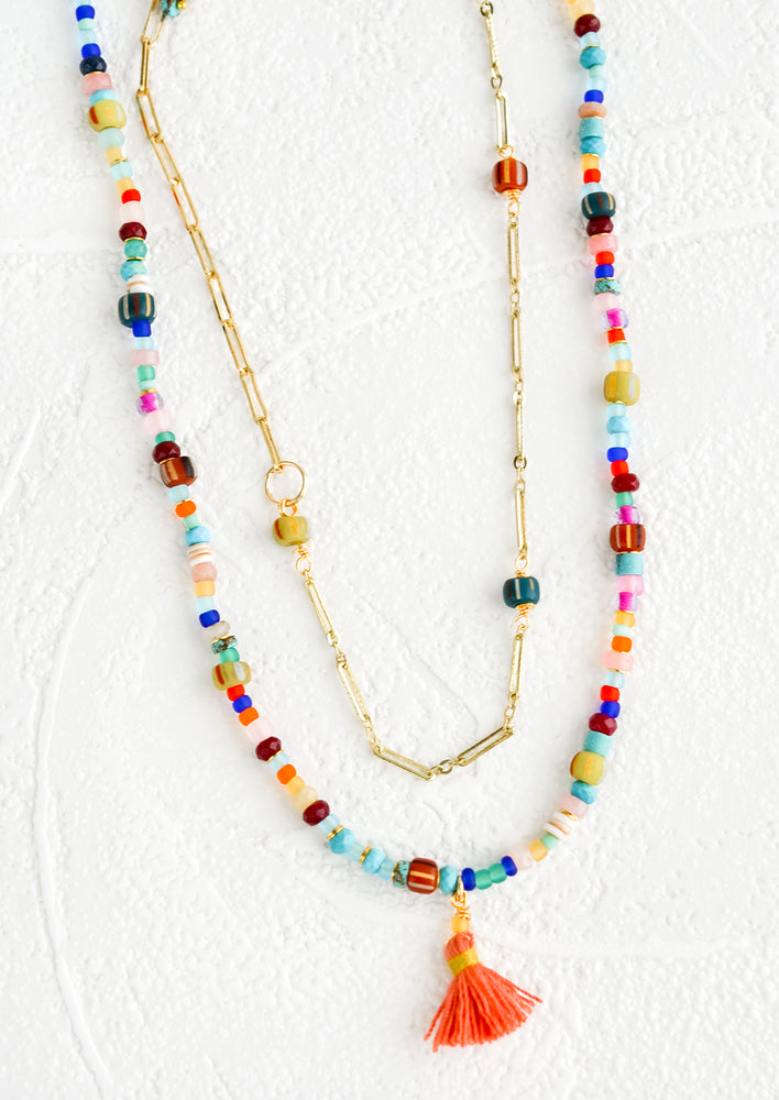 Two layered necklace with colorful beaded outer layer and gold chain inner layer.