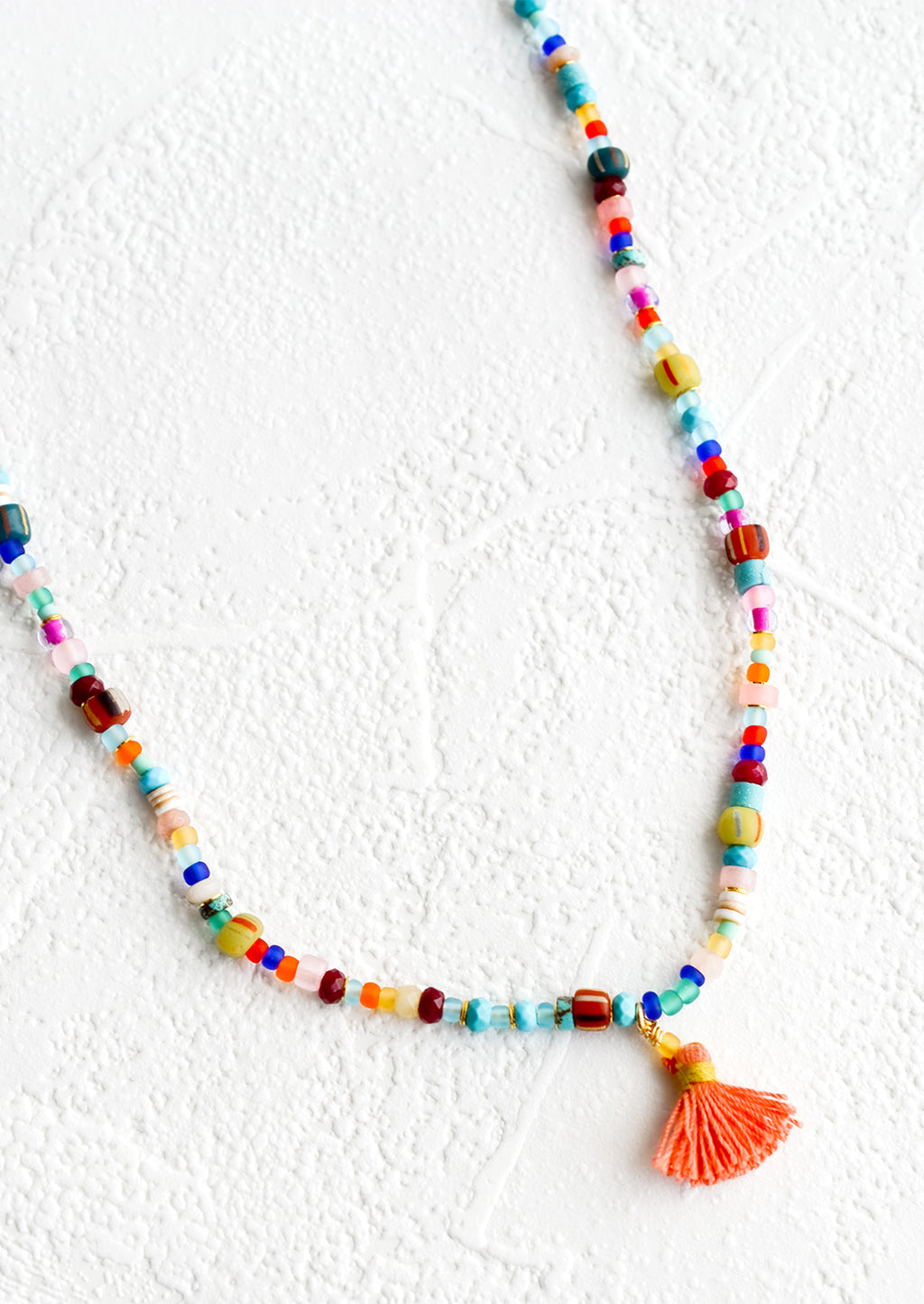 2: Colorful beaded necklace with peach tassel at center.