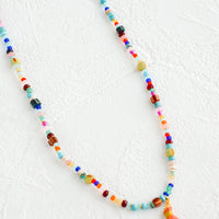 3: Colorful beaded necklace with peach tassel at center.