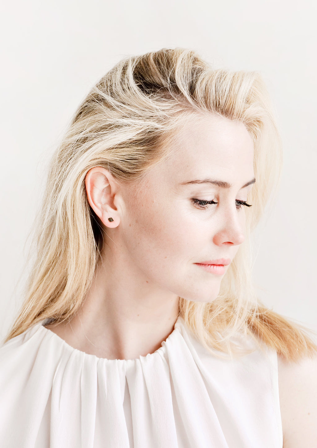 3: Model wears stud earrings and white blouse.