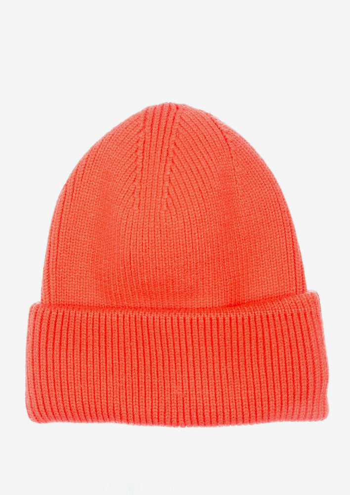 A knit beanie with oversized cuff in coral orange color.