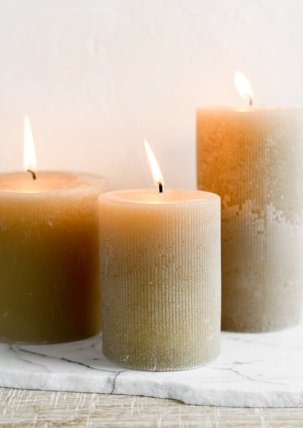 2: Three tan colored pillar candles in assorted sizes.