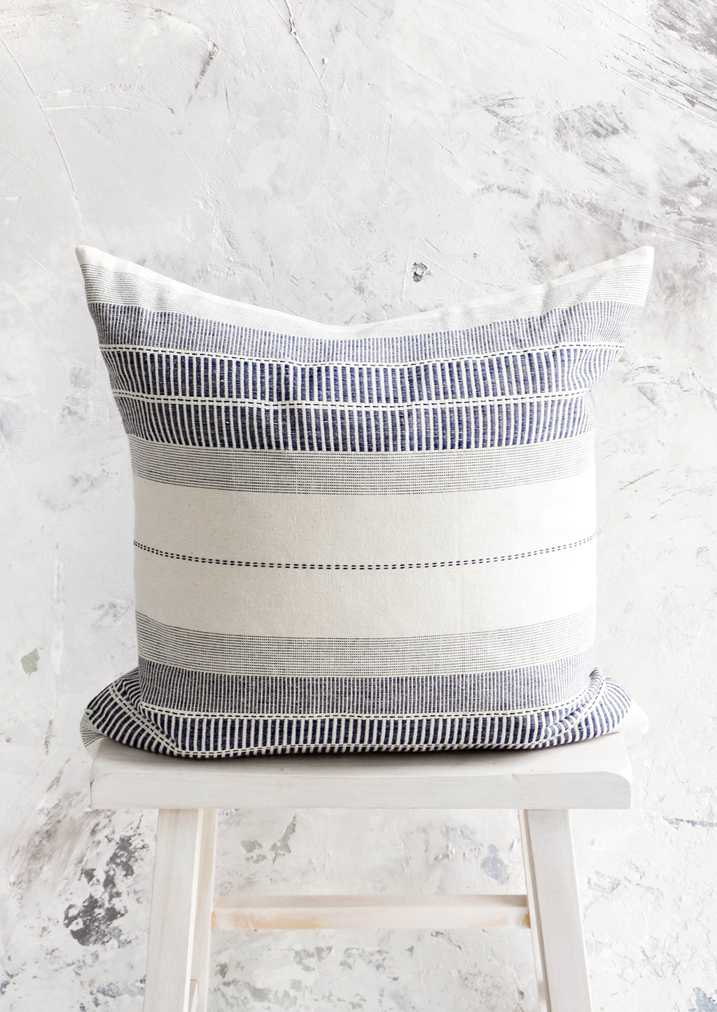 1: Square throw pillow in natural cotton with blue embroidery in striped patterns.