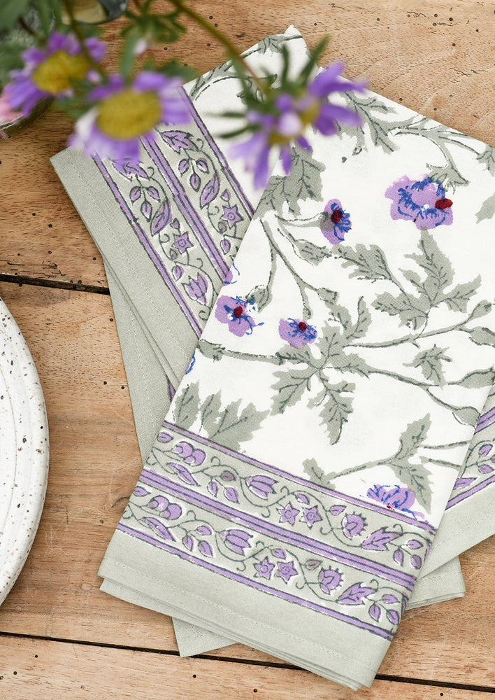 A pair of block printed cotton napkins in green and purple floral print.