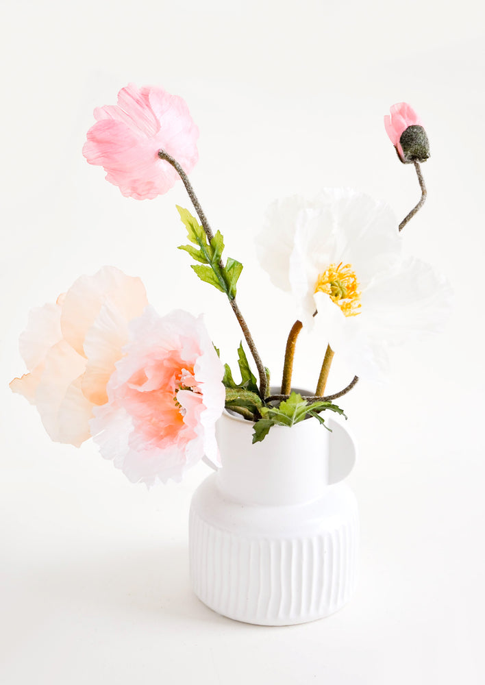 Whimsical, white ceramic vase with ribbed texture, pictured with pink flowers