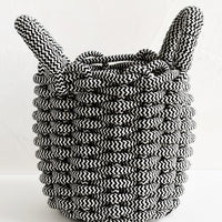 1: A black and white woven rope basket with top handles.