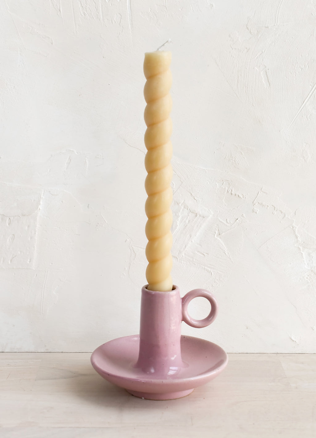 5: A pink taper holder holding a twisted taper candle.