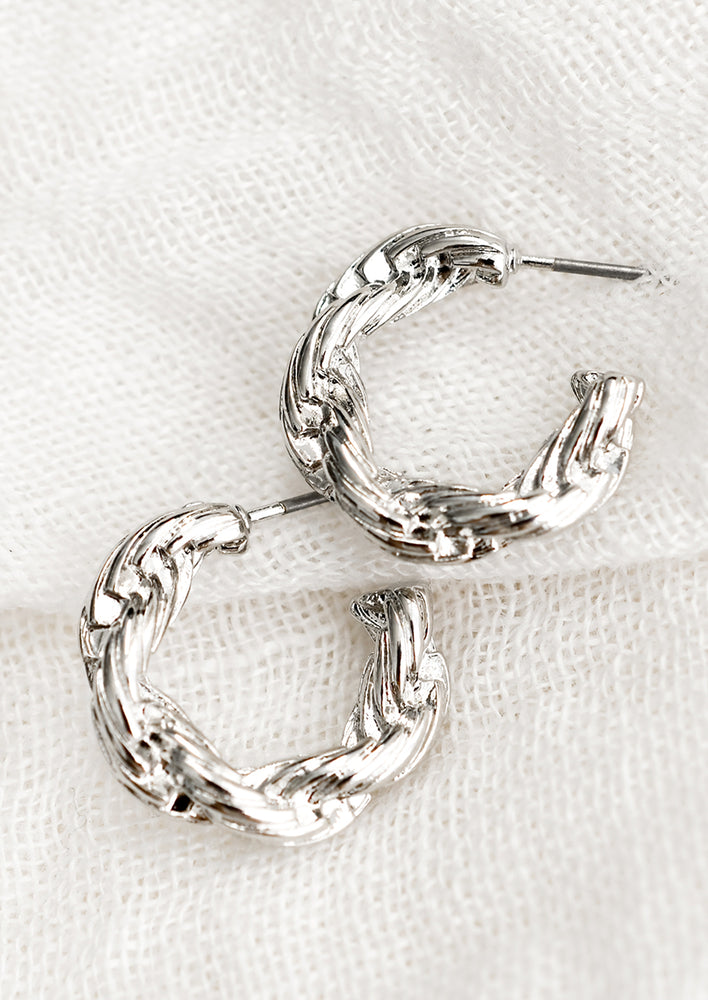 1: A pair of silver-tone hoop earrings with twisted rope texture.