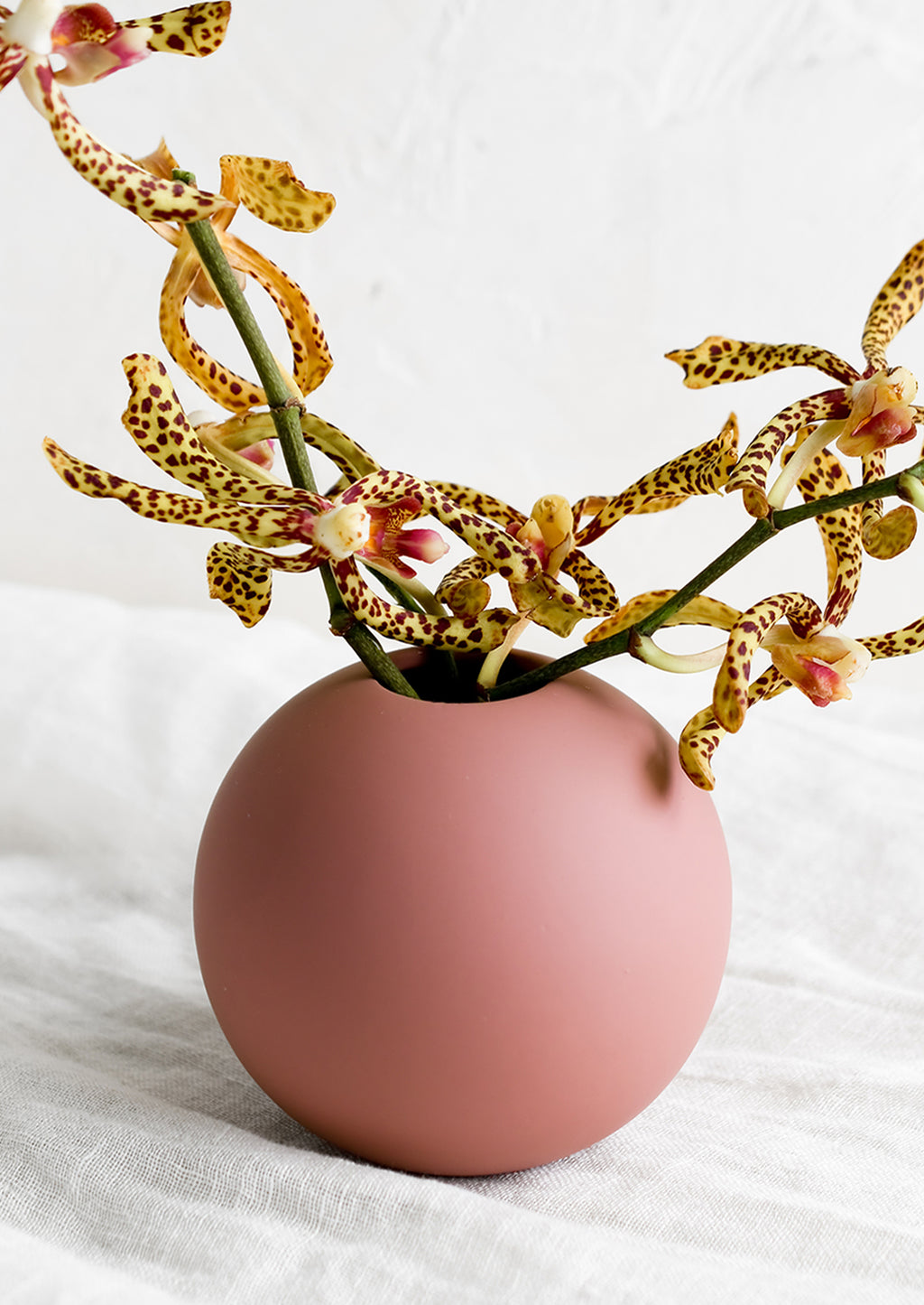 1: A round matte vase in dusty rose color, with tiger lilies.