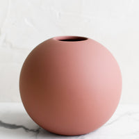2: A round matte orb-shaped vase in dusty rose color.