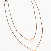 3: Two layer necklace composed of one dark gold chain with translucent pink crystal pendant and one of dark gold chain and pink freshwater pearl pendant.