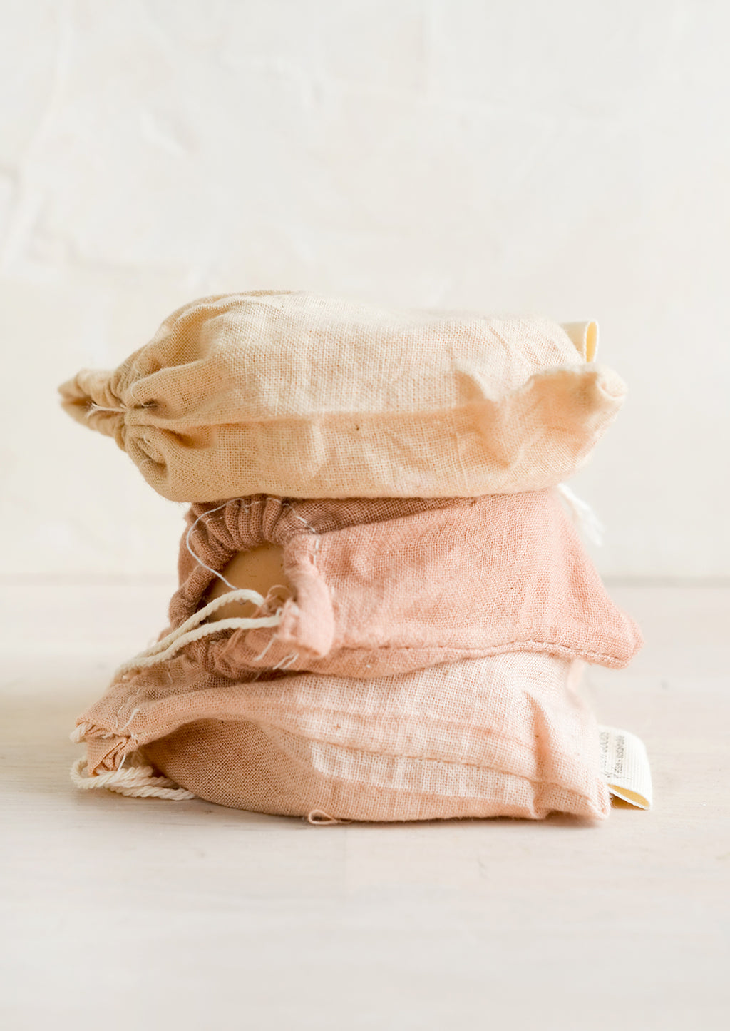 3: A stack of naturally dyed muslin pouches holding soap.