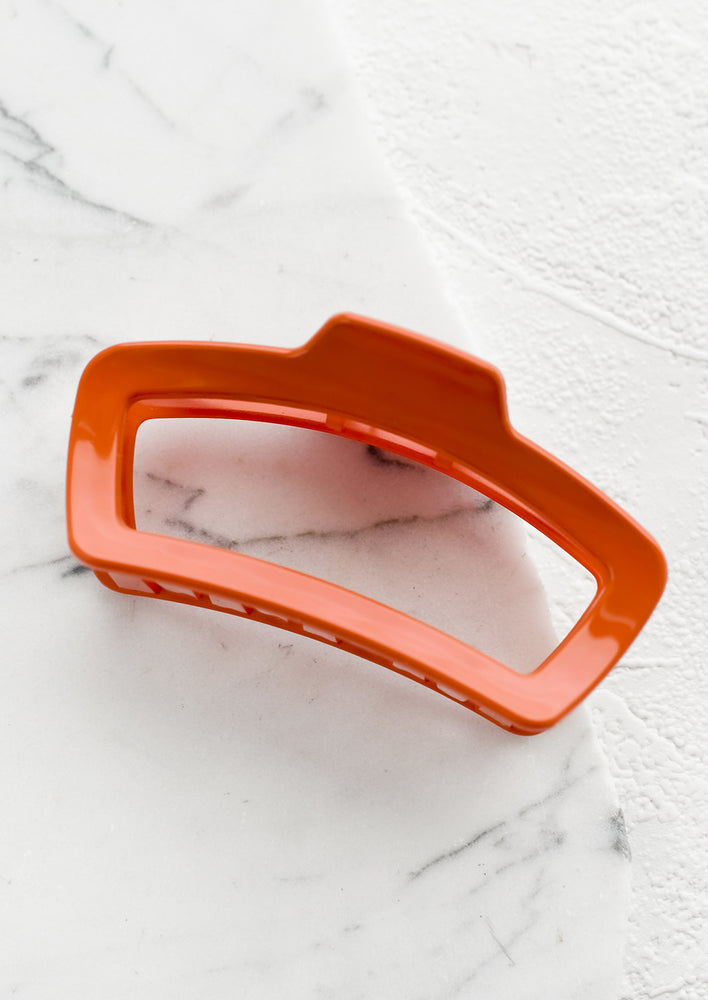 A rounded rectangle hair claw in persimmon.