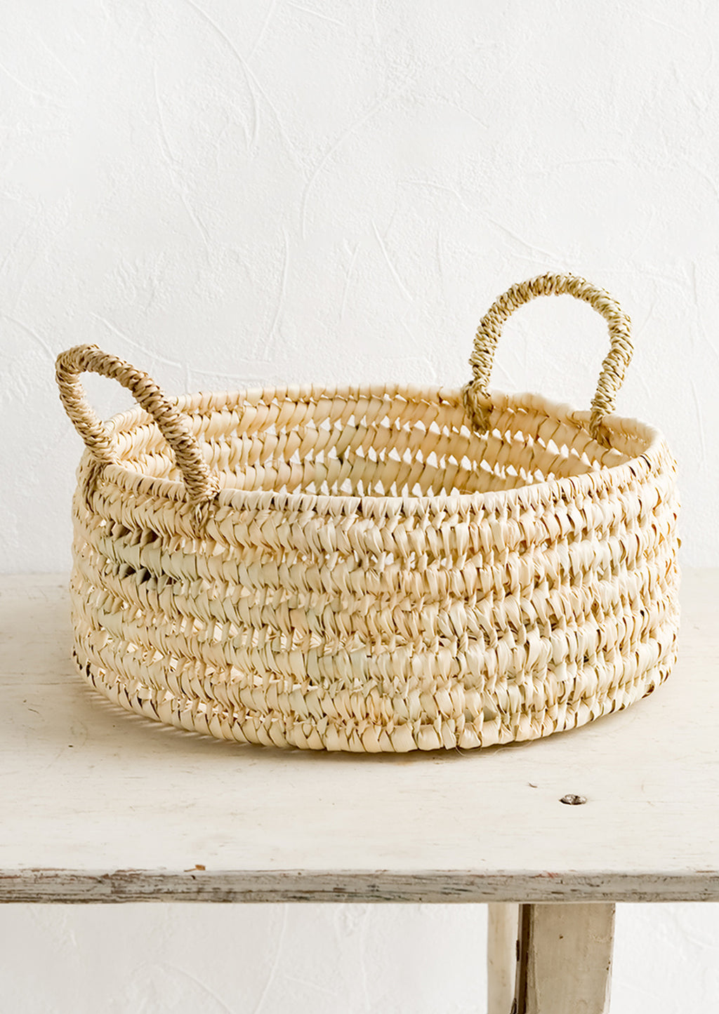 2: A round shallow storage basket made from dried palm leaf.