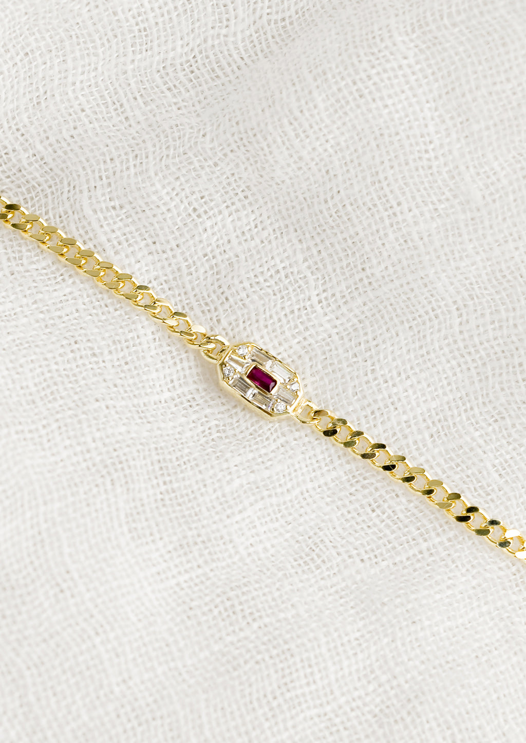 2: A gold chainlink bracelet with baguette ruby and crystal charm.