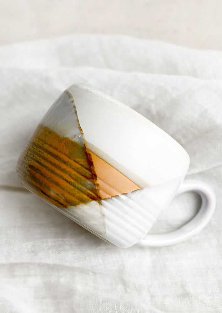 A mug with mix of brown and white glazes forming geometric pattern.