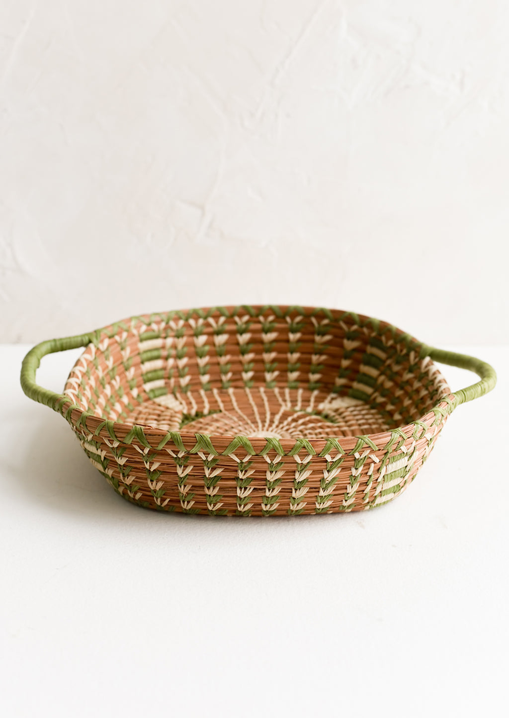 2: A shallow basket in rounded square shape with rectangular green handles at sides.