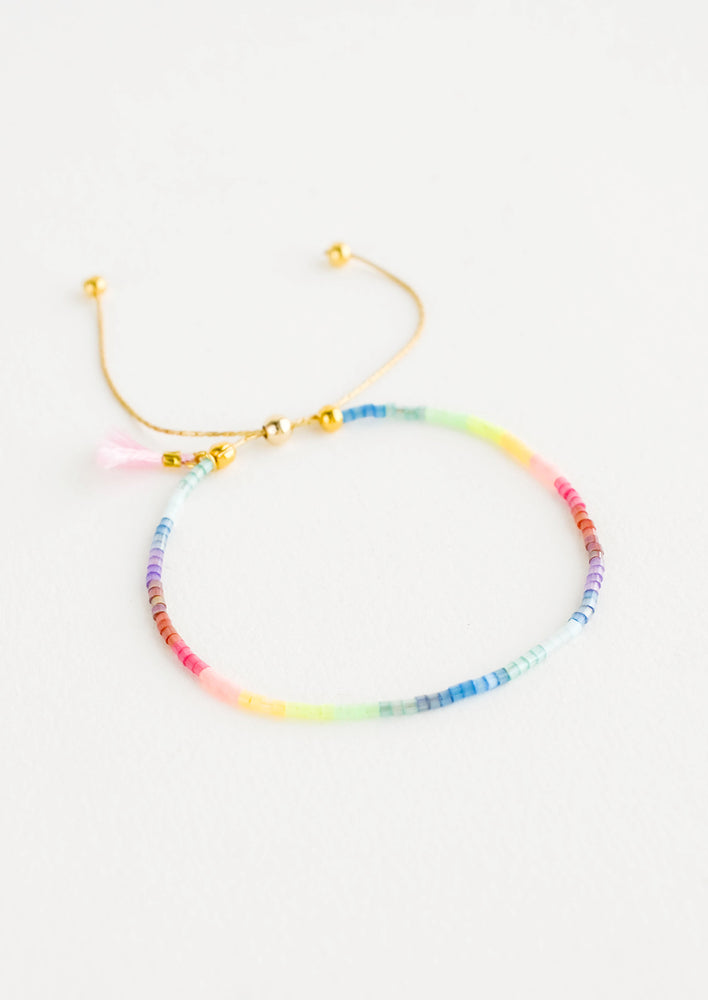 Delicate bracelet of rainbow colored glass beads on a thin gold chain.
